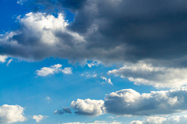 istock Blue sky with beautiful fluffy white and dark clouds glows from sun beating through clouds. Delight and pleasure. 1210800754