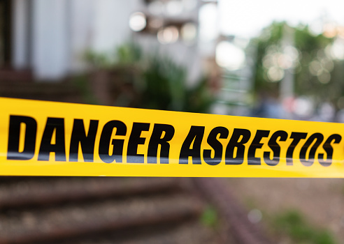 Yellow cordon tape warning of asbestos danger at the entrance to a house being renovated.