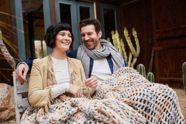 istock Smiling couple talking together on a bench outside their home 1210804041