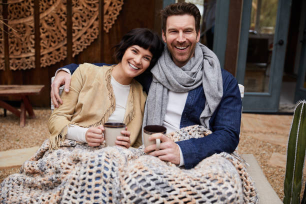 istock Smiling couple sitting outside with coffees on a cool morning 1210804780