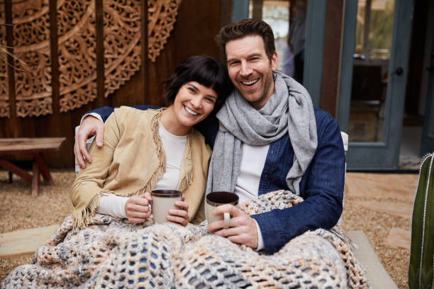 istock Smiling couple drinking coffee on a bench outside on a cool morning 1210804847