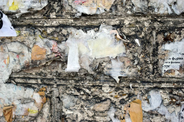istock A brick wall covered with scraps of paper and ads 1210806415