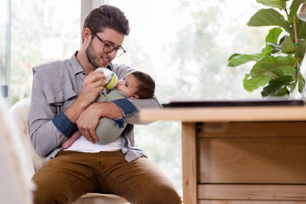 istock Dad sits at desk and feeds baby bottle 1210806706