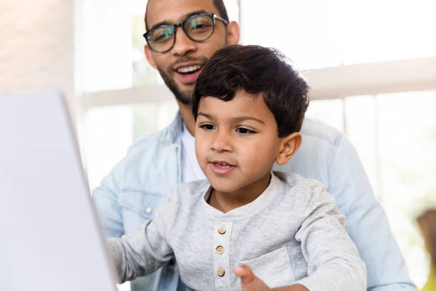 istock Little boy uses laptop with his dad 1210807303