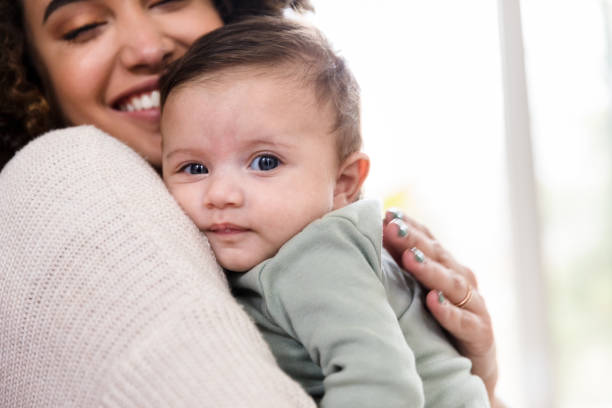 istock New baby looks at camera while smiling mom holds him 1210807890