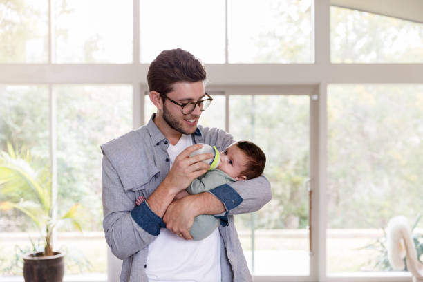 istock Young father holds baby snugly while feeding him bottle 1210807906