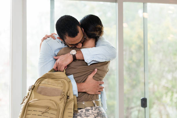 istock As he hugs soldier wife, husband holds her backpack 1210807972