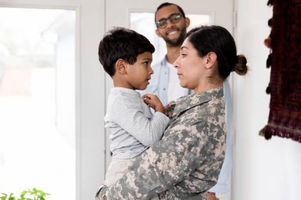istock Dad smiles while watching son talk to soldier mom 1210807983