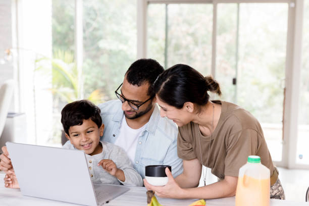 istock Family laughs together when playing on laptop at kitchen counter 1210808003