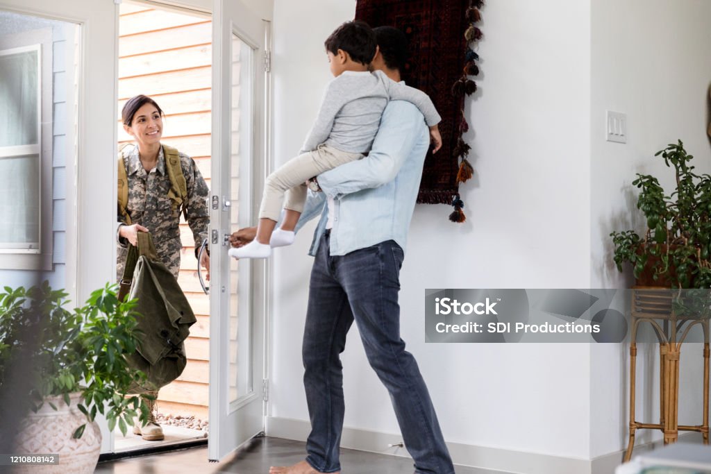 Soldier returns home Excited female soldier returns home from a long deployment. She is greeted by her husband and preschool age son. Home Interior Stock Photo