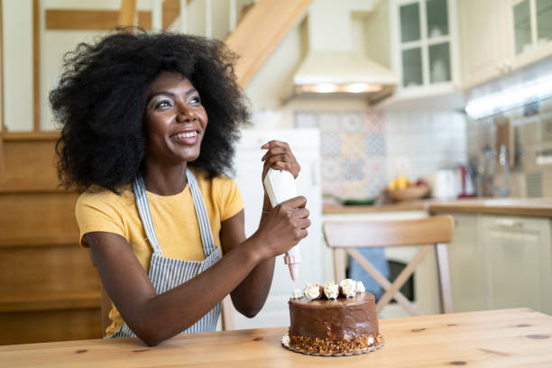 istock African woman decorating birthday cake at home, making faces 1210808678