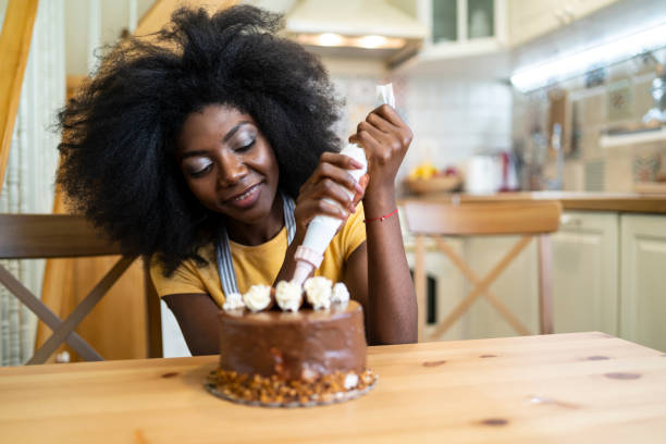 istock African woman decorating birthday cake at home, making faces 1210808681