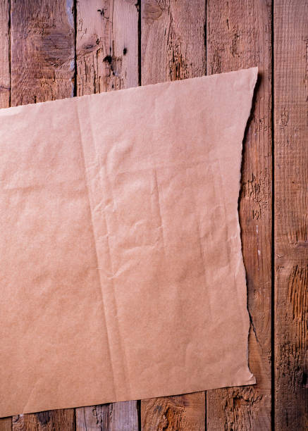 hoja de papel marrón sobre un fondo de tablón rústico. - paper craft brown wrinkled fotografías e imágenes de stock