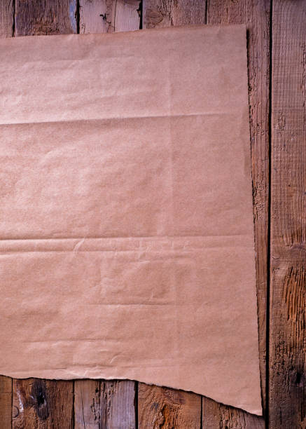 hoja de papel marrón sobre un fondo de tablón rústico. - paper craft brown wrinkled fotografías e imágenes de stock