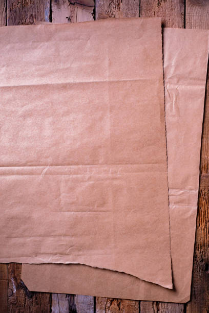 folha de papel marrom em um fundo de prancha rústica. - paper craft brown wrinkled - fotografias e filmes do acervo