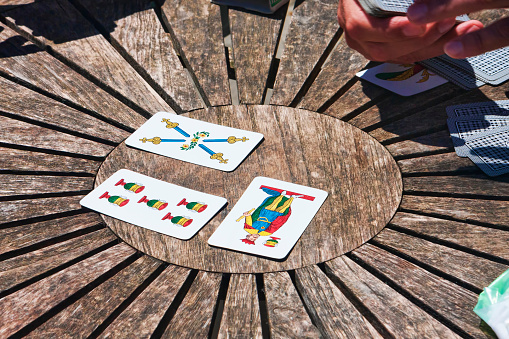 Mesa circular de madera con cuatro cartas de colores, la gente disfruta de las cartas napolitanas tradicionales y jugar juego de triunfo photo
