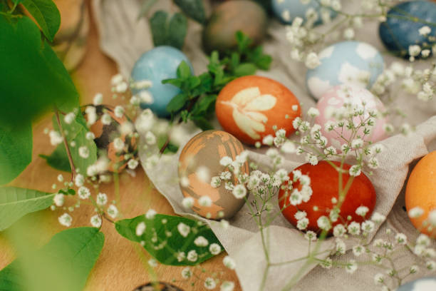 istock Easter eggs with modern minimal ornaments painted with natural dye on rustic background. Stylish colorful Easter eggs on wooden table with spring flowers and green branches. Zero waste holiday 1210814259
