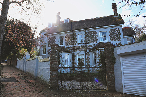 Eastbourne, England - March 03, 2020: A large traditional country house in rural East Sussex behind a high stone wall - street view.