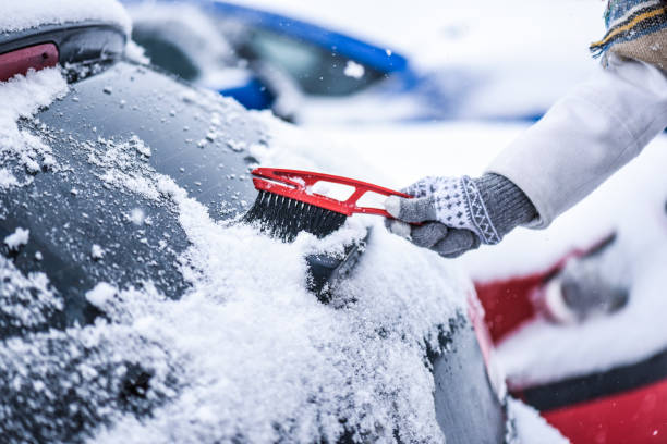 フロントガラスから雪を掃除する女性、凍った氷のガラスを削る。冬の車のクリーンフロントウィンドウ - snow car window ice scraper ストックフォトと画像
