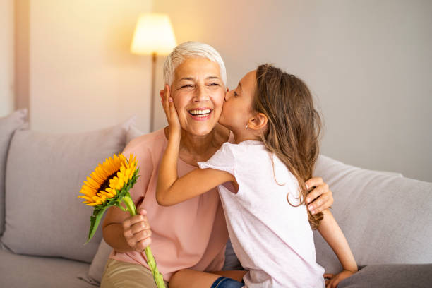 celebrare la festa della mamma o il concetto dell'8 marzo - grandmother giving gift child foto e immagini stock