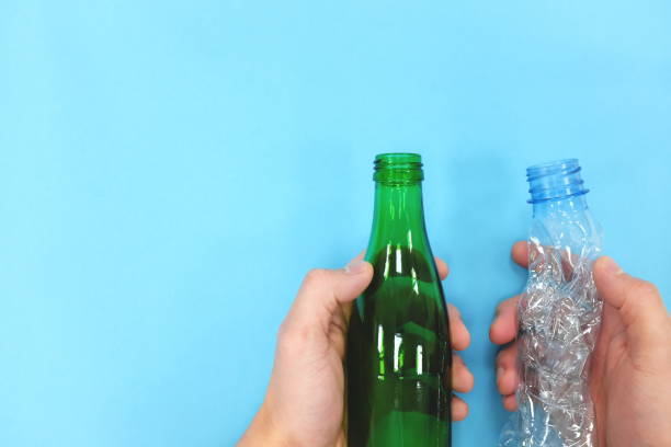 istock Hands holding a reusable glass bottle and a plastic bottle in blue background. Reduce reuse recycle concept. 1210817015