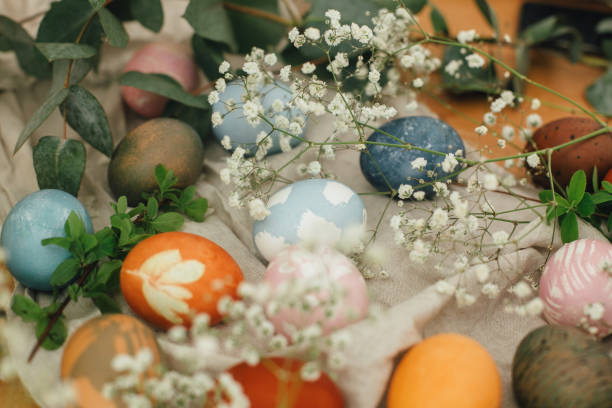 istock Modern easter eggs painted with natural dye on rustic background with flowers. Zero waste holiday. Stylish colorful Easter eggs on wooden table with spring flowers and green branches 1210817035