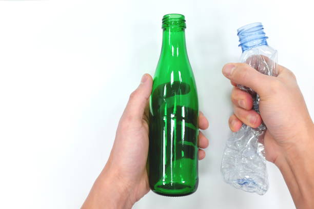 istock Hands holding a reusable glass bottle and a plastic bottle in white background. Zero waste concept. 1210817062