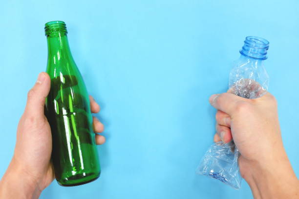 istock Hands holding a reusable glass bottle and a plastic bottle in blue background. Reduce reuse recycle concept. 1210817065