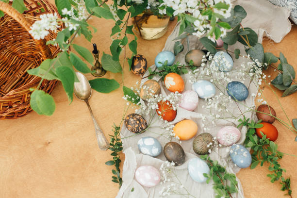 istock Easter eggs on rustic background with basket, candle, spring flowers and green branches. Stylish colorful Easter eggs with modern ornaments painted with natural dye. Rural flat lay 1210817097
