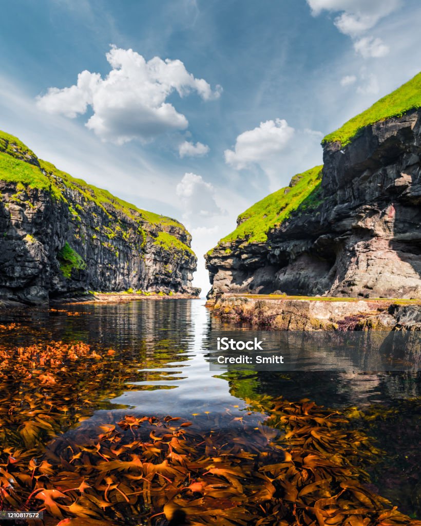 Beautiful view of dock with clear water and red seaweed Beautiful view of dock or harbor with clear water and red seaweed in Gjogv village, Eysuroy island, Faroe Islands, Denmark. Landscape photography Faroe Islands Stock Photo