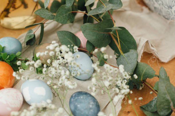 istock Easter eggs with modern minimal ornaments painted with natural dye on rustic background. Stylish colorful Easter eggs on wooden table with spring flowers and green branches. Zero waste holiday 1210817867