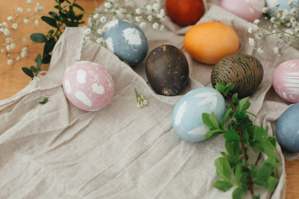 istock Easter eggs with modern minimal ornaments painted with natural dye on rustic background. Stylish colorful Easter eggs on wooden table with spring flowers and green branches. Zero waste holiday 1210818766