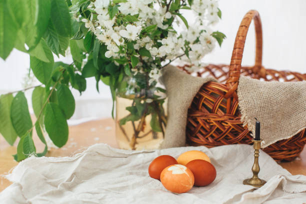 istock Modern Easter eggs  on rustic table with spring flowers, candle,  basket. Stylish red and yellow Easter eggs painted in natural dye from onion and turmeric. Happy Easter 1210819930