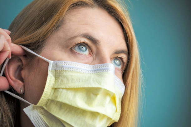 istock Woman Putting Protective Face Mask On 1210820002