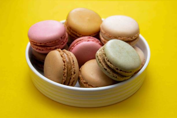istock Colorful macaroons cookies dessert on a plate, with yellow background. 1210820174