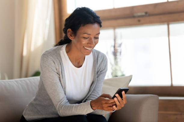 istock Happy biracial woman relax on sofa using smartphone 1210820256