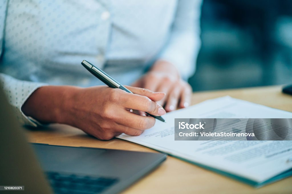 Businesswoman checking agreement before signing. Close-up shot of a businesswoman holding a pen and signing contract. Contract Stock Photo