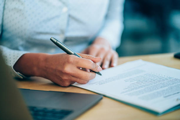 Businesswoman checking agreement before signing. Close-up shot of a businesswoman holding a pen and signing contract. agreement stock pictures, royalty-free photos & images