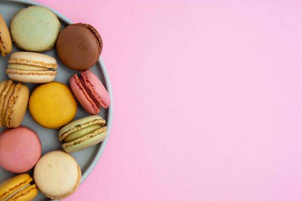 bunte makronen cookies dessert auf einem teller, mit rosa hintergrund und kopierraum, top-ansicht. - plate dishware stack multi colored stock-fotos und bilder