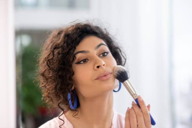 istock Dark-haired woman applying powder on her face 1210820727