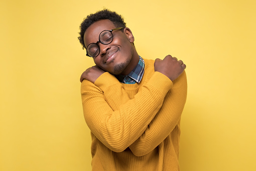Hombre afroamericano con ropa amarilla y gafas se abraza photo