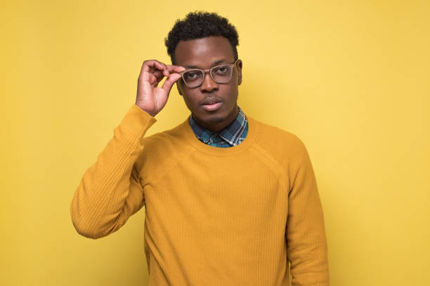 istock man in yellow clothes wearing glasses looking at camera carefully 1210823040