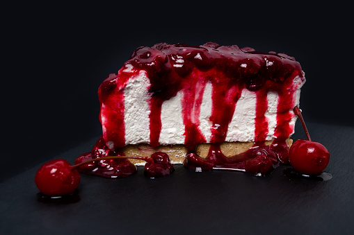 Cheesecake with cherries on dark slate stone board