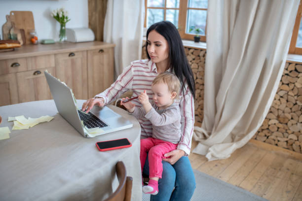 istock Mom working at laptop, holding her daughter 1210824211