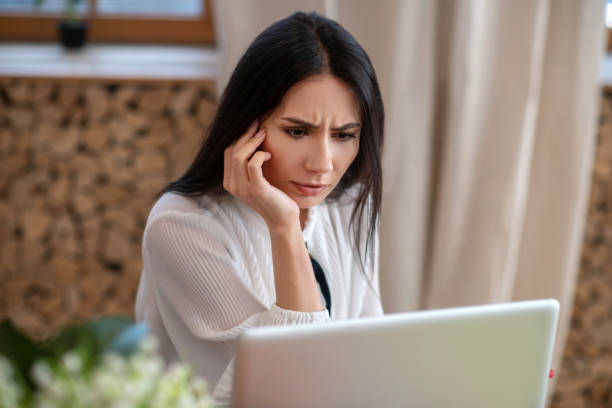 istock Young woman sitting at computer, holding hand under chin 1210824381