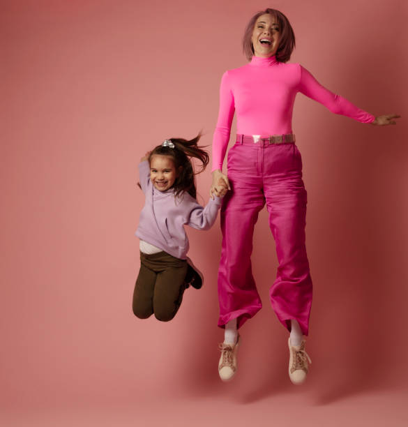 мать и дочь двух человек лучшая дружба прыгает в воздухе студии выстрел перед розовым фоном - family daughter isolated full length стоковые фото и изображения