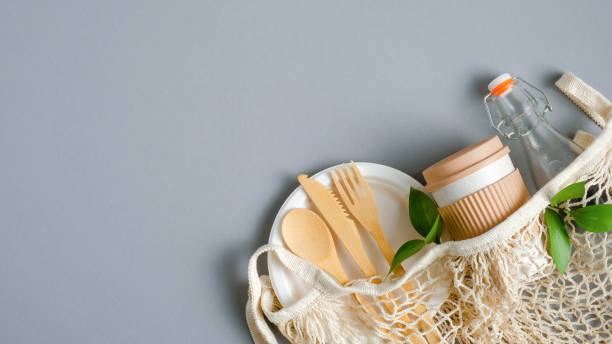 istock Eco friendly travel cutlery set, cup and bottle in mesh bag on grey background. Zero waste, plastic free concept. Sustainable lifestyle 1210825633