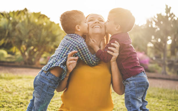 glückliche mutter spaßig mit ihren beiden söhnen spielen im freien - liebe und familie konzept - fokus auf mutter gesicht - people child twin smiling stock-fotos und bilder