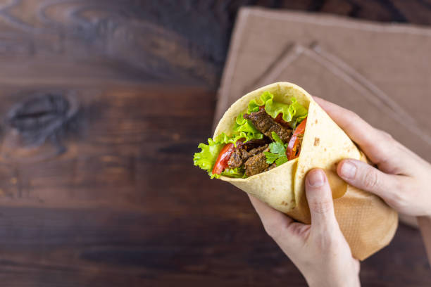 istock Burrito with beef in female hands 1210829083