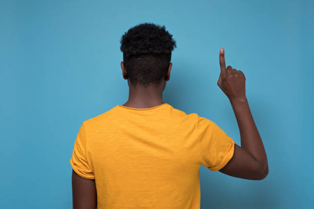 istock Back view of pointing up blackman. gesticulating showing on copyspace. 1210831117